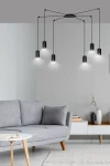Lampa wisząca Traker 6-punktowa w kolorze czarnym, z sześcioma cylindrycznymi kloszami zawieszonymi na cienkich linkach. Ujęcie frontalne, lampa umieszczona w nowoczesnym wnętrzu z szaro-beżową kanapą i minimalistycznym stolikiem.