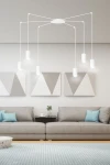 Lampa wisząca Traker 6-punktowa w kolorze białym z okrągłym stropem, sześcioma zawieszonymi oprawami w formie cylindrów. Zawieszona w nowoczesnym wnętrzu z szarymi grafikami na ścianach, nad szarym narożnikiem i stolikiem kawowym.