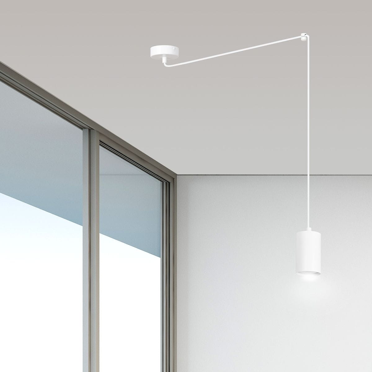 Lampa wisząca Traker 1-punktowa w kolorze białym, zawieszona na cienkim, prostym przewodzie. Posiada cylindryczny klosz, emitujący światło w dół, umieszczony na długim ramieniu przymocowanym do sufitu. Tło jasne, minimalistyczne.