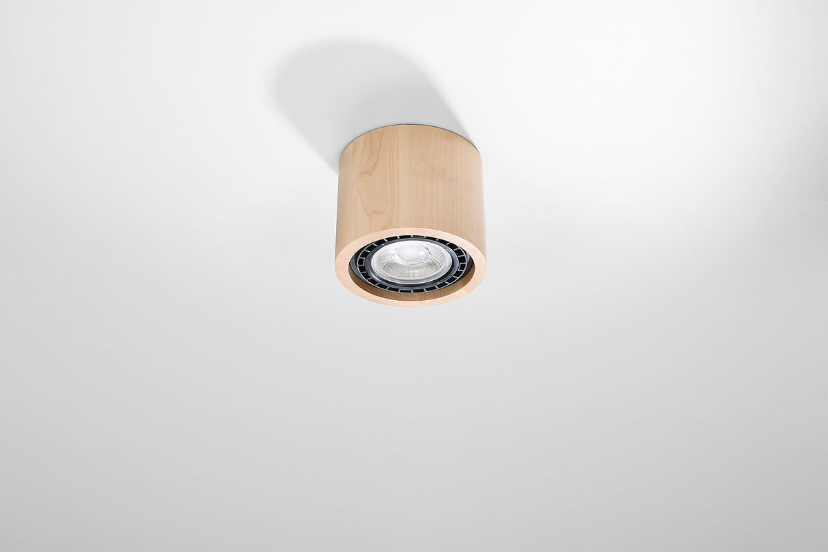 Lampa sufitowa 1-punktowa z drewna w kształcie cylindrycznym. W kolorze jasnego drewna, z widoczną lampą wewnętrzną. Ujęcie frontalne, zamontowana na białym suficie, podkreślająca minimalistyczny styl.