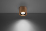 Lampa sufitowa 1-punktowa z drewna w kolorze jasnego drewna, zamontowana na szarym suficie. Okrągła obudowa z wykończeniem w naturalnym kolorze, z widoczną żarówką wewnątrz, emitująca światło w dół. Prosty, nowoczesny design.