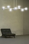 Lampa wisząca Rossi 8-punktowa w białym i grafitowym kolorze, zawieszona na dwóch cienkich kablach. Posiada osiem okrągłych kloszy z przezroczystego szkła, rozmieszczonych na prostokątnej ramie. Tło w neutralnym odcieniu, mebel obok w ciemnym kolorze.