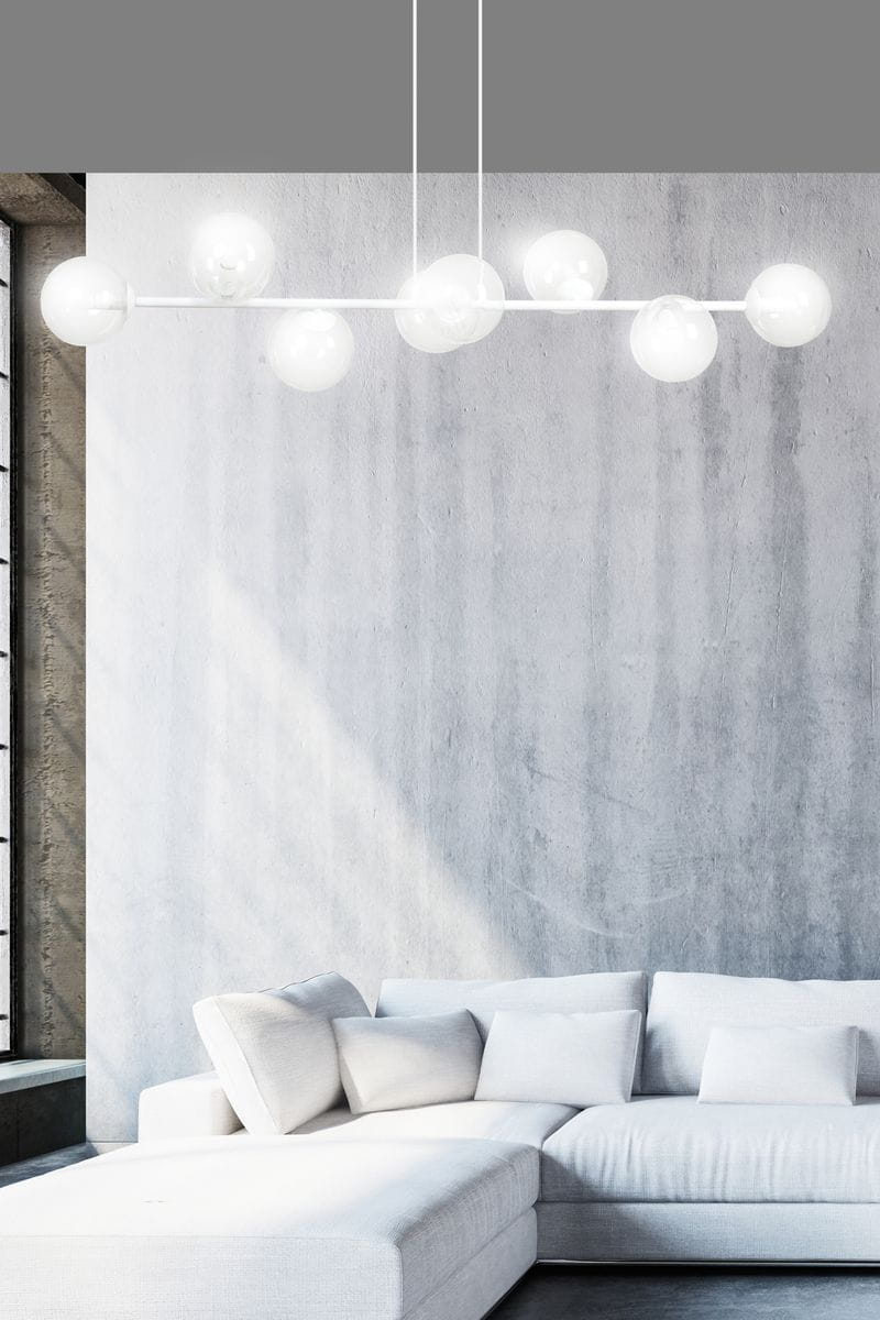 Lampa wisząca Rossi 8-punktowa w kolorze białym i transparentnym, z ośmioma kulistymi kloszami. Ujęcie z dołu, zawieszona na trzech linkach, w nowoczesnym wnętrzu z szarymi ścianami i jasną sofą.