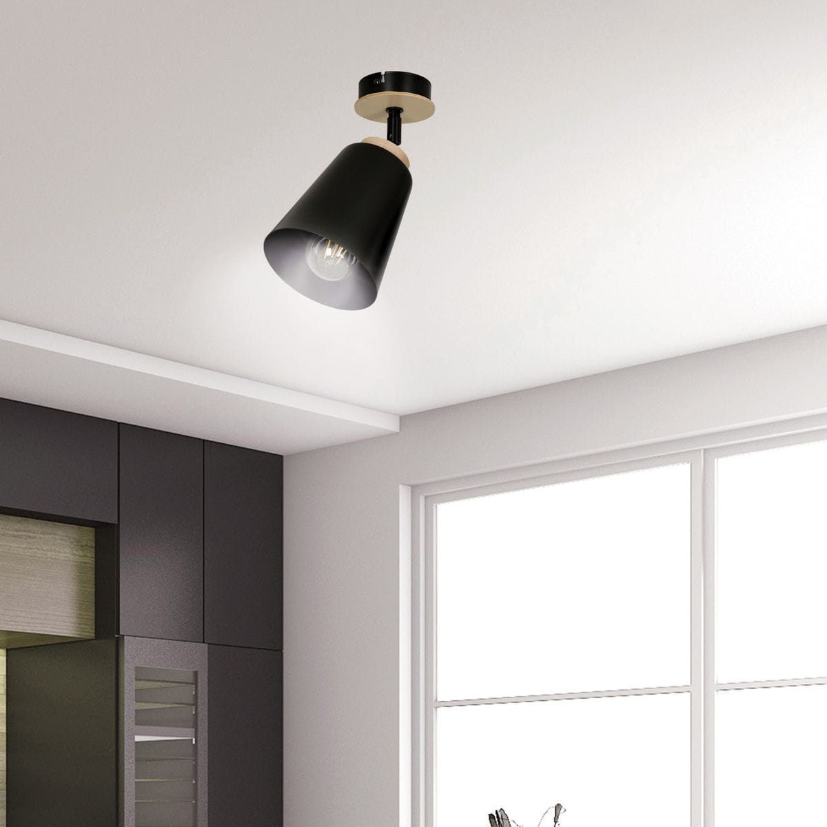 Czarna lampa sufitowa Atlas 1-punktowa w kształcie stożka, zawieszona na metalowym mocowaniu. Widoczna żarówka wewnątrz klosza. Produkt umieszczony w nowoczesnym wnętrzu z ciemnymi meblami i dużym oknem.