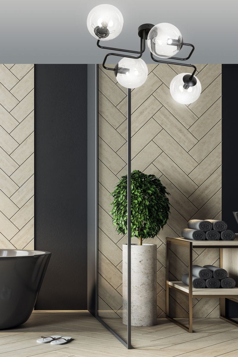 Brendi lampa sufitowa 4-punktowa, transparentna, z czarnym metalowym mocowaniem i okrągłymi kloszami. Zawieszona na suficie w nowoczesnym wnętrzu, w tle widoczne elementy dekoracyjne, takie jak roślina w donicy oraz ręczniki na półce.