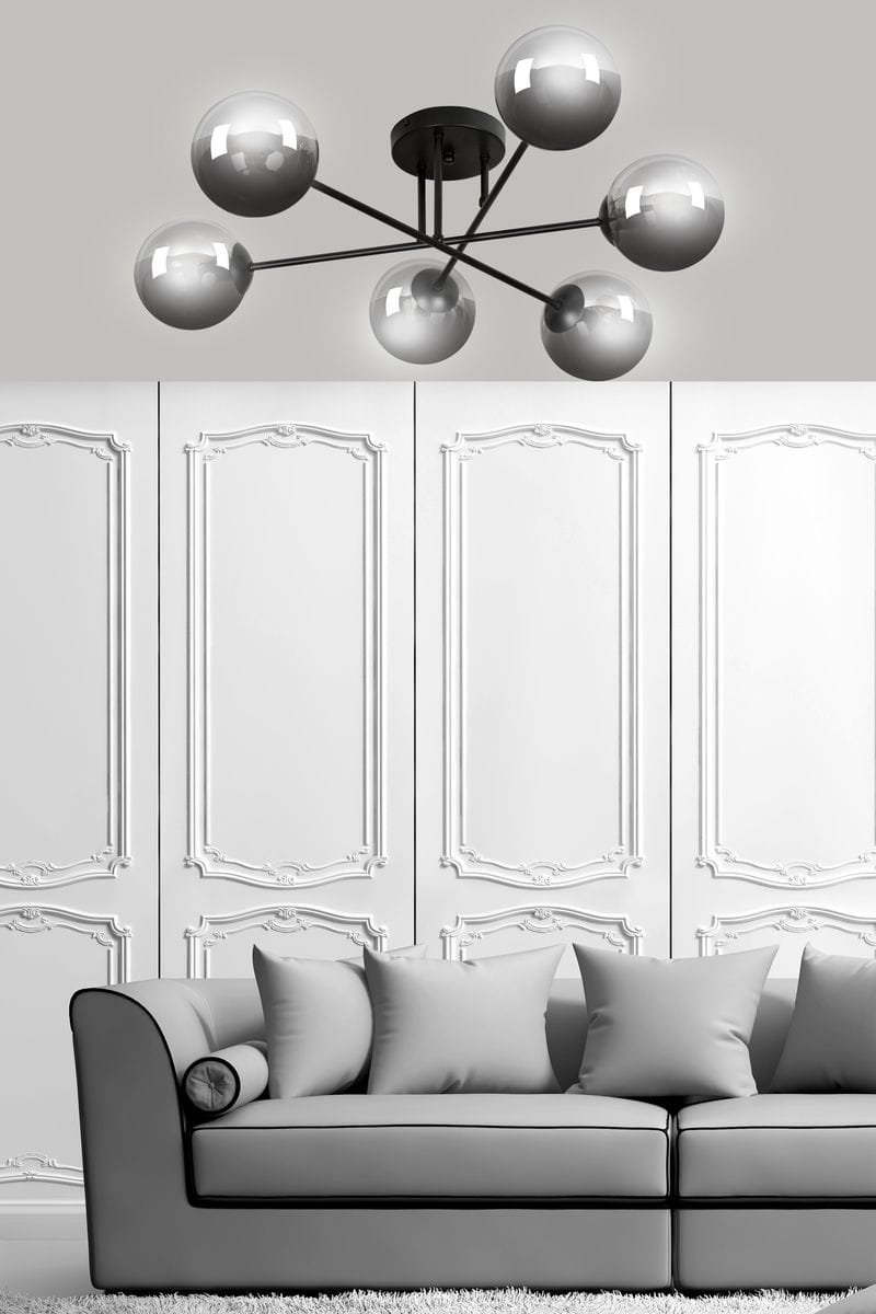 Lampa sufitowa Brendi B 6-punktowa w kolorze grafitowym, z sześcioma kulistymi kloszami, zamontowana na okrągłej podstawie. Produkt widoczny na tle eleganckiej, białej ściany i szarej kanapy.