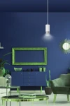 Lampa wisząca Fumiko 1-punktowa w białym kolorze z chromowanymi detalami, zawieszona na cienkim przewodzie, emituje światło w nowoczesnym wnętrzu. Tło w intensywnym granacie z zielonymi akcentami mebli i roślinami.