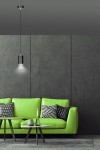 Lampa wisząca Fumiko 1-punktowa w kolorze czarnym z chromowanym detalem, zawieszona na cienkim przewodzie, o cylindrycznym kształcie. W tle widoczna zielona sofa z poduszkami w geometryczne wzory, na szarym tle.