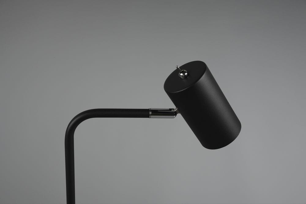 Czarna lampa stołowa Marley 1-punktowa, z metalowym kloszem o cylindrycznym kształcie. Uchwyt w formie prostego ramienia, z chromowanym detalem. Lampa ustawiona w kącie, na jednolitym tle.