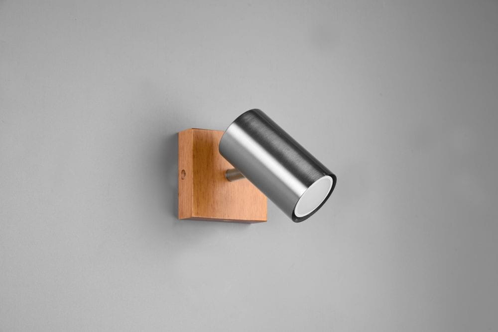 Kinkiet Marley 1-punktowy w kolorze niklu z drewnianą podstawą. Lampa w formie cylindrycznego reflektora, zamontowana na ścianie, skierowana lekko w dół. Prosty design, idealny do nowoczesnych wnętrz.