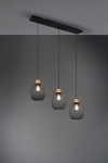 Lampa wisząca Calimero 3-punktowa z trzema kloszami w kształcie sześcianu, wykonana z siatki metalowej w kolorze czarnym z drewnianymi akcentami u góry. Zawieszona na czarnym stelażu, umieszczona na tle szaro-beżowej ściany.