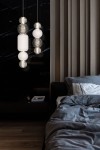 Lampa wisząca Collar LED w kolorze chromu, składająca się z okrągłych i owalnych elementów szklanych, w tym białych i przezroczystych kul. Zawieszona w pionie, w nowoczesnym wnętrzu z ciemnym tłem i drewnianymi akcentami.