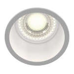 Oprawa sufitowa do zabudowy 1-punktowa w kolorze białym, z okrągłą, gładką obudową. Środek lampy z przezroczystym kloszem, który zawiera źródło światła. Ujęcie z góry, ukazujące detal konstrukcji oraz efekt świetlny.