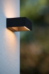 Goa LED kinkiet elewacyjny w kolorze czarnym, prostokątny, zamontowany na jasnej ścianie. Emituje ciepłe światło, z widoczną szczeliną na górze. Produkt w pozycji stojącej, w zbliżeniu na detal wykonania.