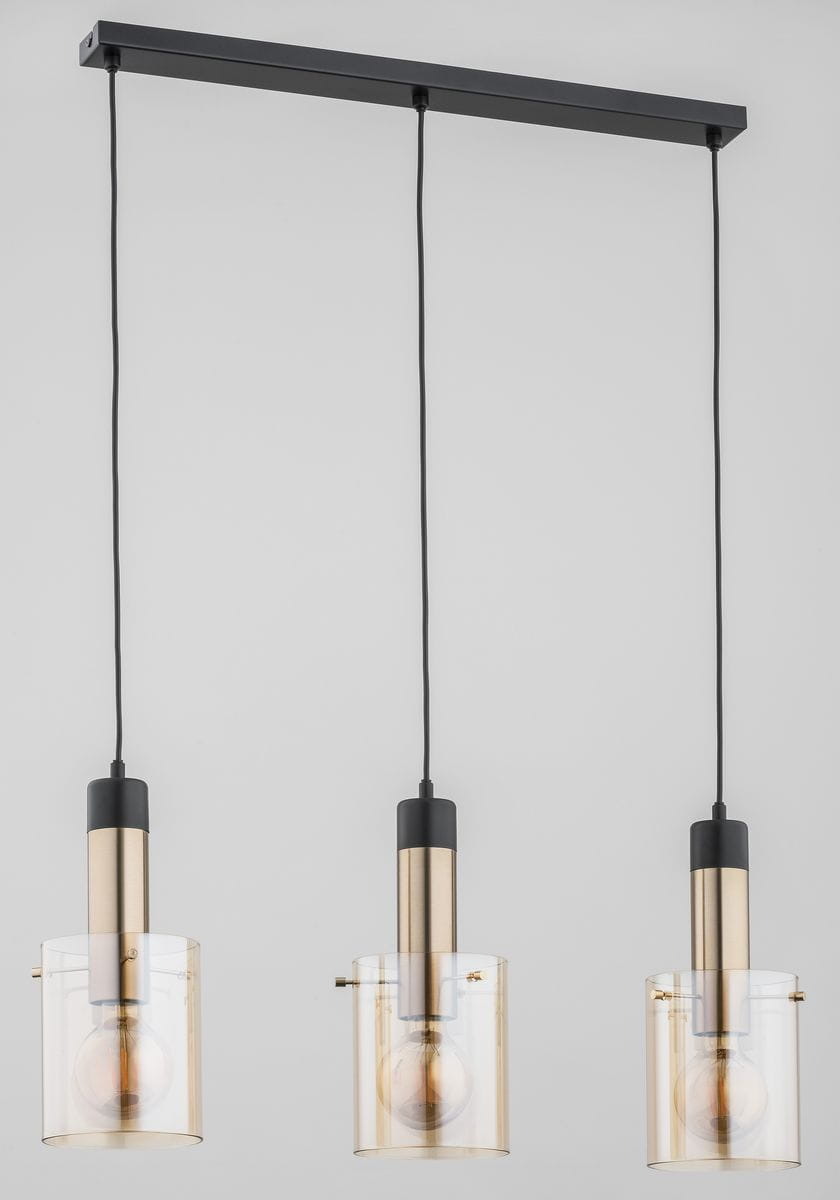 Lampa wisząca Bella 3-punktowa z metalowymi, złotymi elementami i przezroczystymi kloszami. Ułożona podwieszona na czarnym stelażu, z trzema źródłami światła w równych odstępach. Kable w czarnym kolorze. Tło jasnoszare.