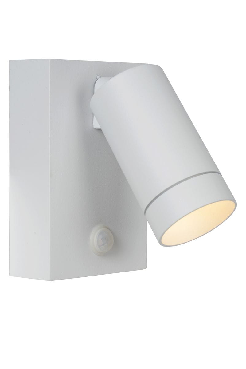 Kinkiet elewacyjny ścienny Taylor z czujnikiem ruchu w kolorze białym. Lampa w kształcie cylindrycznym, montowana na prostokątnej podstawie. Widoczny czujnik ruchu na dolnej części podstawy. Dobrze oświetlona żarówka skierowana w dół.