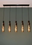 Czarna lampa wisząca Orlando z pięcioma punktami świetlnymi. Szklane klosze w cylindrycznym kształcie, zawieszone na czarnych przewodach. Lampa mocowana do sufitu za pomocą prostokątnej podstawy. Tło w odcieniu zieleni.