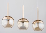 Lampa wisząca Volda 3-punktowa w złotym kolorze, składająca się z trzech okrągłych kloszy z przezroczystego szkła. Klosze mają metalowe, złote kaptury i są zawieszone na cienkich linkach. Produkt widoczny na jednolitym tle.