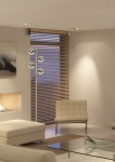 Lampa podłogowa Tycho 4-punktowa w kolorze mosiądzu z czterema okrągłymi kloszami w odcieniu srebrnym. Stoi w rogu nowoczesnego wnętrza z jasnymi ścianami i zasłonami, obok białego fotela i szklanego stolika.