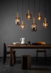 Lampa wisząca Joanet 6-punktowa w czarnym kolorze, składająca się z sześciu szklanych kloszy w różnych rozmiarach, zawieszonych na cienkich czarnych przewodach. Widoczna na tle ciemnej ściany, nad drewnianym stołem z ceramicznymi naczyniami i krzesłami.