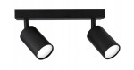 Czarna lampa sufitowa (spot) z dwoma ruchomymi punktami świetlnymi, zamocowana na prostokątnej podstawie. Kąt ujęcia frontalny, ukazujący cylindryczny kształt opraw świetlnych. Prosta, nowoczesna forma.