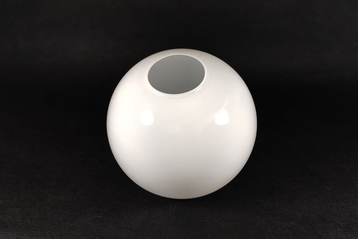 Klosz szklany w kształcie kuli o średnicy 140 mm, wykonany z błyszczącego białego szkła. Widoczny otwór na górze, kąt ujęcia z boku, tło czarne. Idealny do lamp lub jako dekoracja.