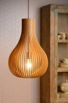 Lampa wisząca Bodo 1-punktowa w jasnym drewnie, w kształcie butelki, z wyeksponowanym żarówką. Ujęcie z przodu, zawieszona na cienkim przewodzie, w tle widoczne meble w stylu vintage.