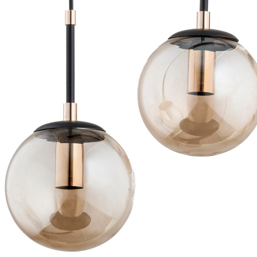 Lampa wisząca Sebia 3-punktowa 61063 w kolorze przezroczystym brązowym z metalowymi elementami w odcieniu złota. Wisi na czarnym przewodzie, z okrągłymi kloszami o gładkiej fakturze, widoczne gniazda na żarówki.