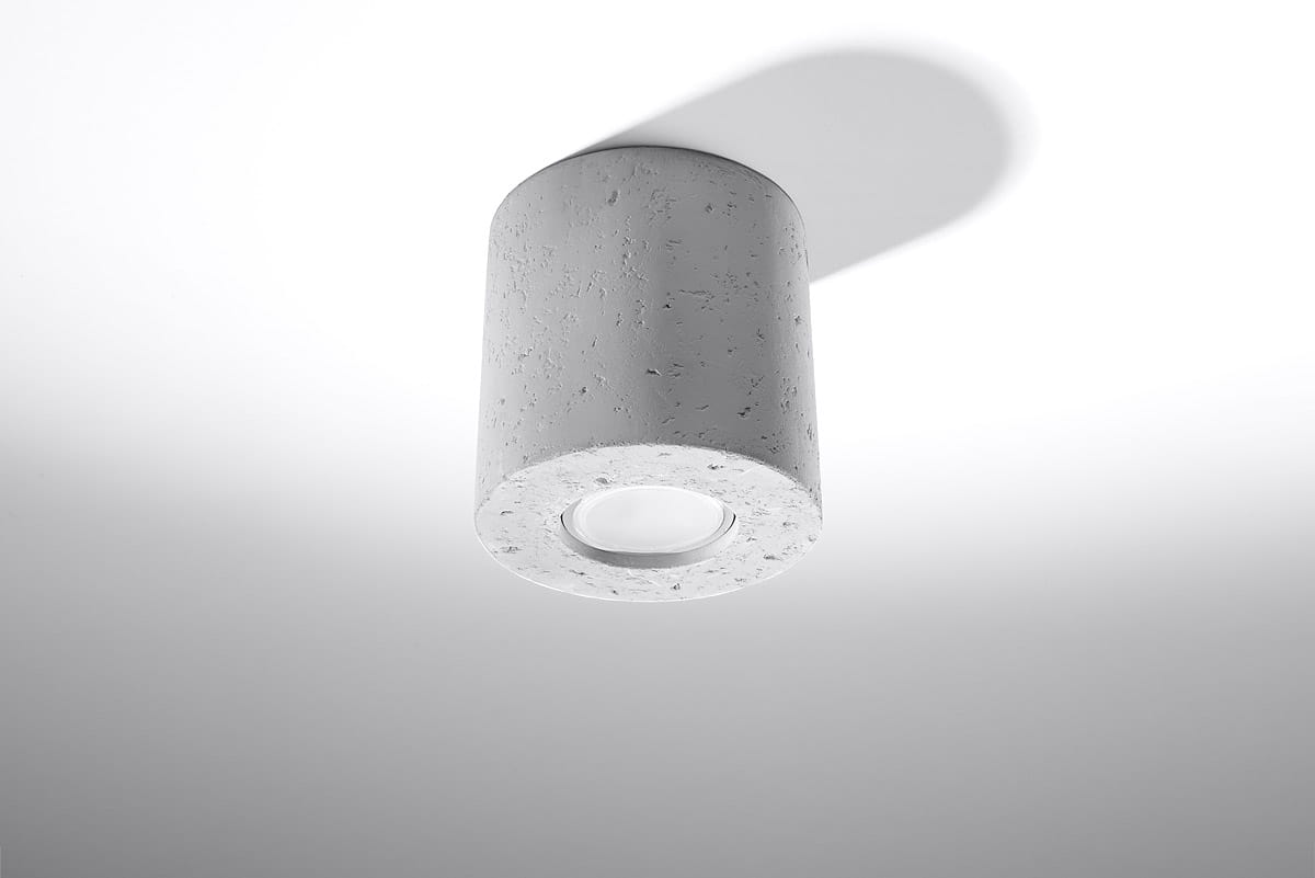 Lampa sufitowa Orbis Beton SL.0488 w kształcie cylindrycznym, wykonana z szarego betonu. Zainstalowana w pozycji wiszącej, z widocznym źródłem światła w dolnej części. Prosty design, idealna do nowoczesnych wnętrz.