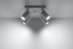 Lampa sufitowa 4-punktowa w kolorze białym, zamontowana na płaskiej podstawie. Cztery cylindryczne reflektory skierowane w różnych kierunkach, emitujące jasne światło. Prosta, nowoczesna forma, idealna do oświetlenia wnętrz.