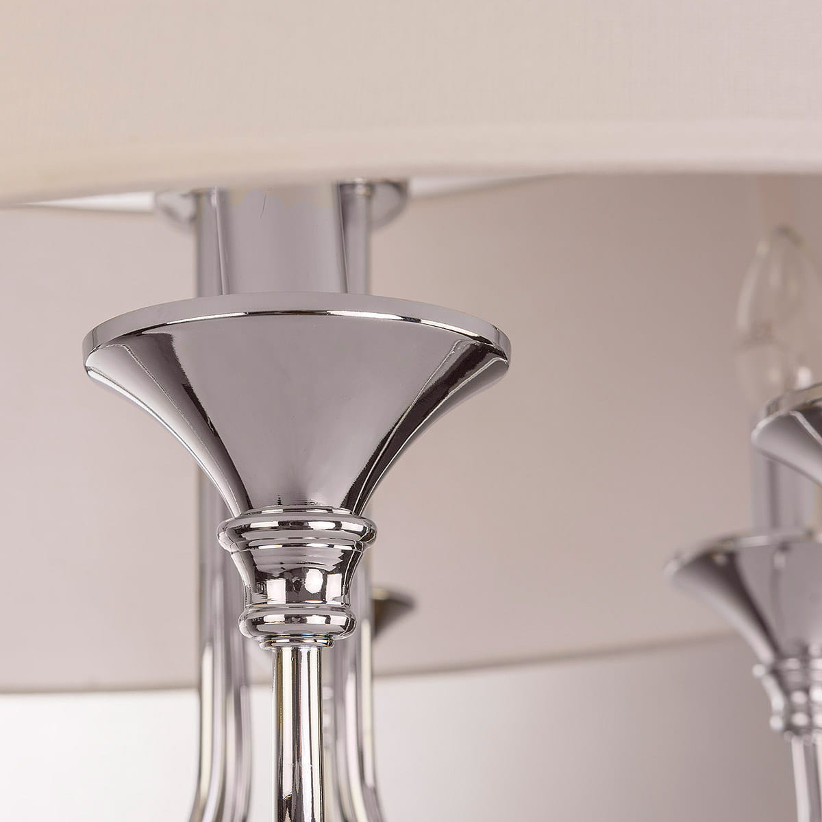 Lampa wisząca Abu Dhabi 6-punktowa, chromowana. Widok z bliska na chromowane elementy mocujące oraz detale konstrukcji. Górna część lampy ma elegancki, lekko wklęsły kształt, z wykończeniem w połysku. Tło neutralne, podkreślające elegancję produktu.