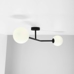 Lampa sufitowa 2-punktowa w kolorze czarnym. Konstrukcja z matowego metalu z dwoma okrągłymi, białymi kloszami. Ujęcie z dołu, ukazujące zamontowaną lampę na białym suficie, z jednym ramieniem skierowanym w lewo, a drugim w prawo.