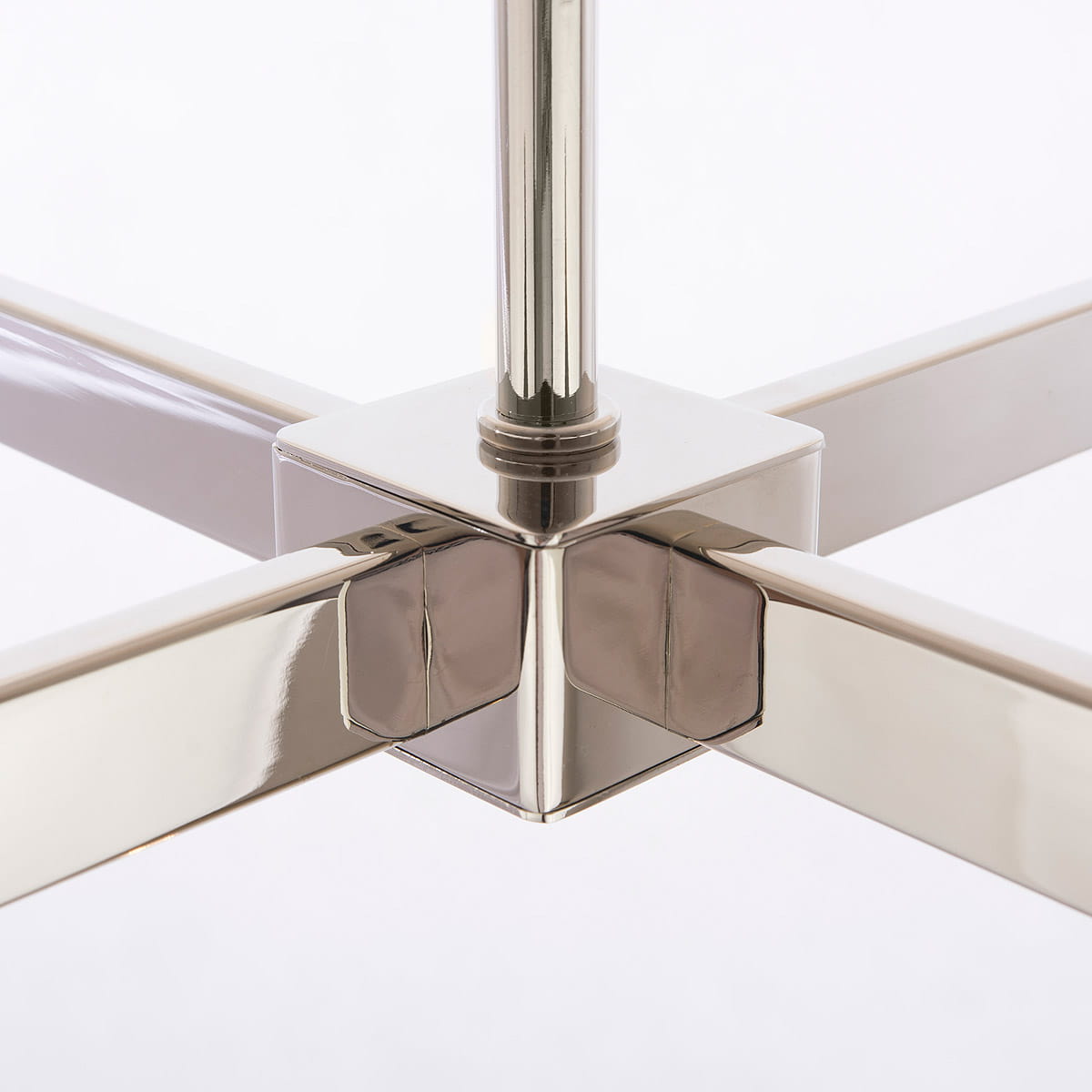 Zbliżenie na chromowane połączenie ramion lampy wiszącej Oxford 4-punktowej. Widoczne eleganckie, prostokątne elementy metalowe, tworzące stabilną konstrukcję. Tło jasne, podkreślające nowoczesny design lampy.