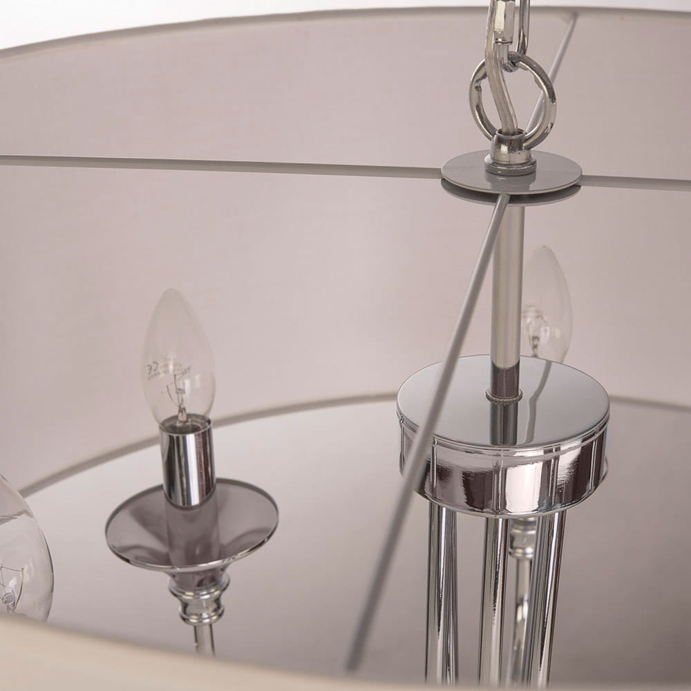 Lampa wisząca Abu Dhabi 6-punktowa w chromie, z okrągłym kloszem. Widoczne chromowane mocowanie i sześć miejsc na żarówki w kształcie łzy. Klosz w jasnym kolorze, z detalami w chromie. Ujęcie z góry, zbliżenie na detale konstrukcyjne.