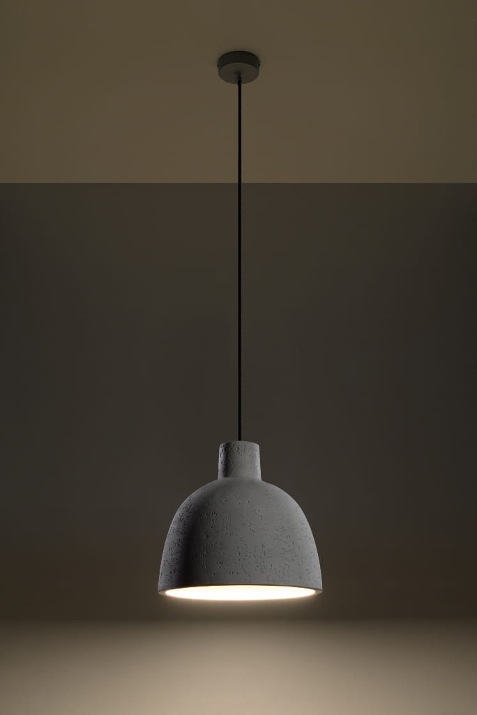 Lampa wisząca Damaso 1-punktowa w kolorze szarym, betonowy klosz o zaokrąglonym kształcie, zawieszona na cienkim przewodzie. Widoczna oprawa z białym źródłem światła, umieszczona pod sufitem w neutralnym tle.