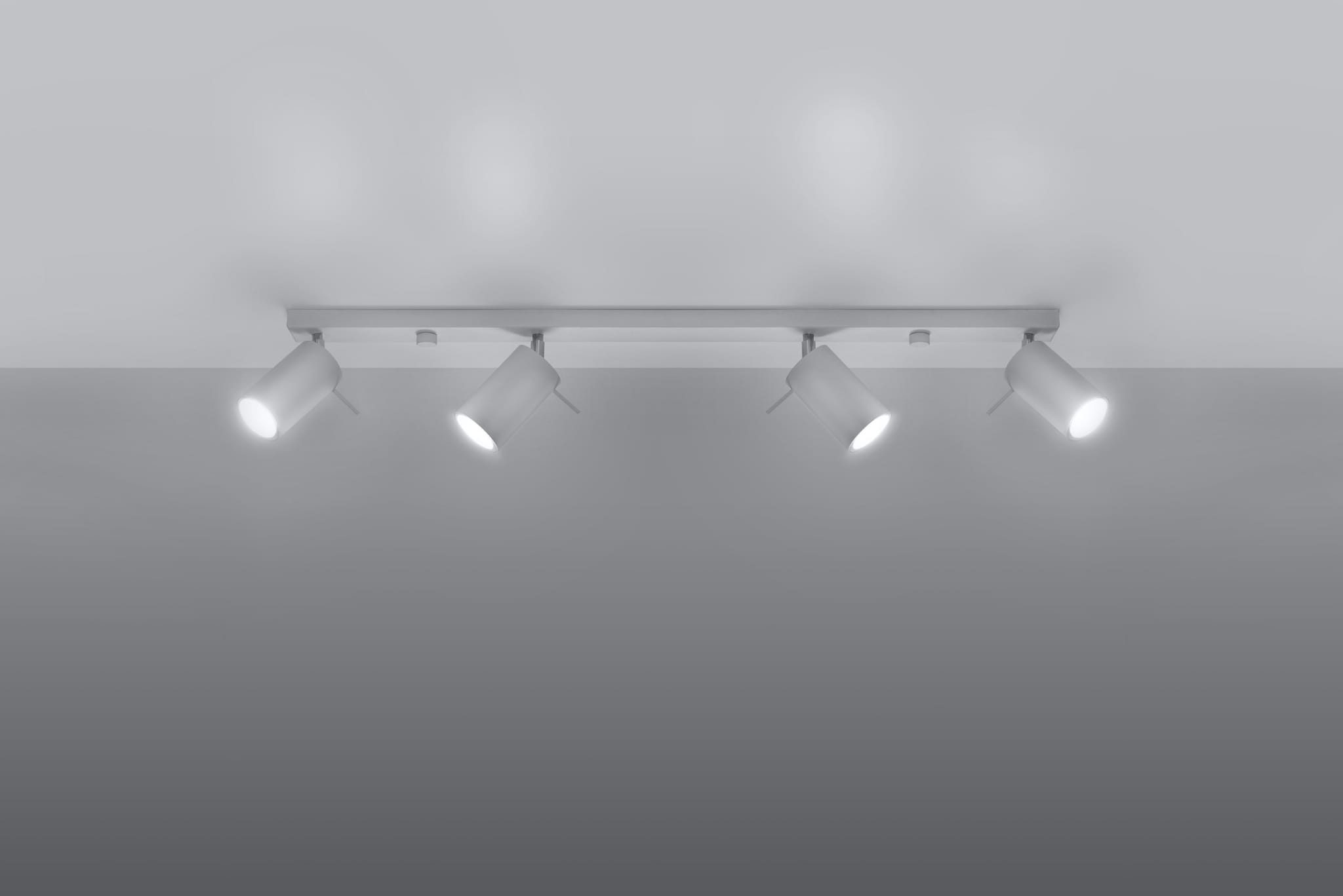 Biała lampa sufitowa 4-punktowa z cylindrycznymi reflektorami, zamontowana na prostokątnej listwie. Reflektory są skierowane w różnych kierunkach, a całość umieszczona na gładkim, jasnym tle.