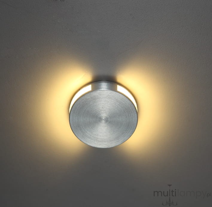 Oprawa schodowa Lesel LED 004 w kształcie okrągłym, wykonana z matowego metalu w kolorze srebrnym. Zamontowana na suficie, emituje ciepłe światło wokół krawędzi, tworząc delikatny efekt oświetlenia.