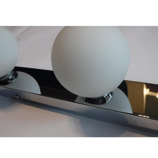 Brazos kinkiet 3-punktowy w kolorze chromu, z trzema matowymi kulistymi kloszami. Kinkiet zamontowany na prostokątnej, lustrzanej podstawie, z widocznymi mocowaniami. Idealny do nowoczesnych wnętrz.