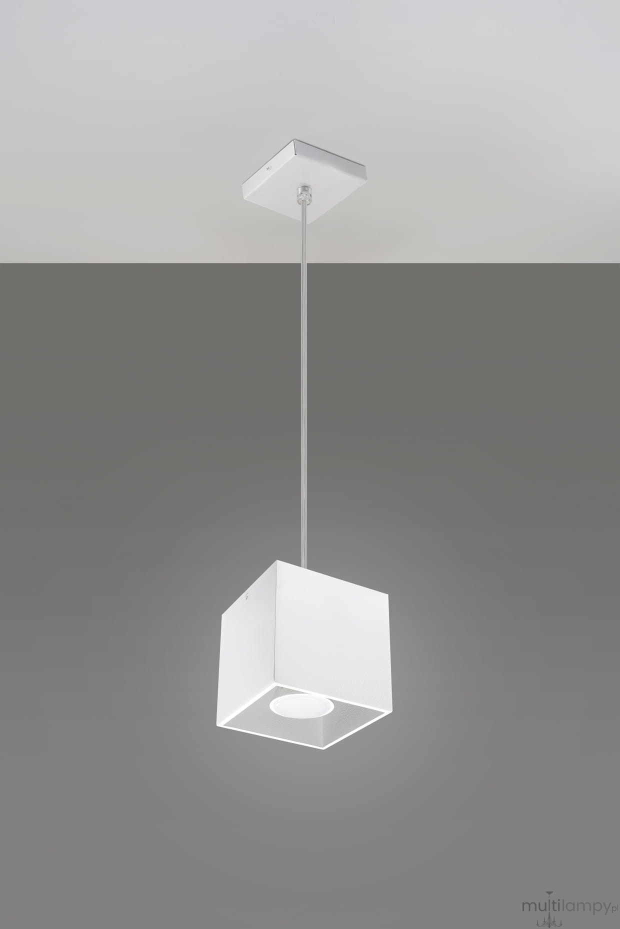 Biała lampa wisząca 1-punktowa Quad, o kwadratowym kształcie, zawieszona na cienkim przewodzie, z płaskim, okrągłym źródłem światła wewnątrz. Ujęcie z góry, na szarym tle.