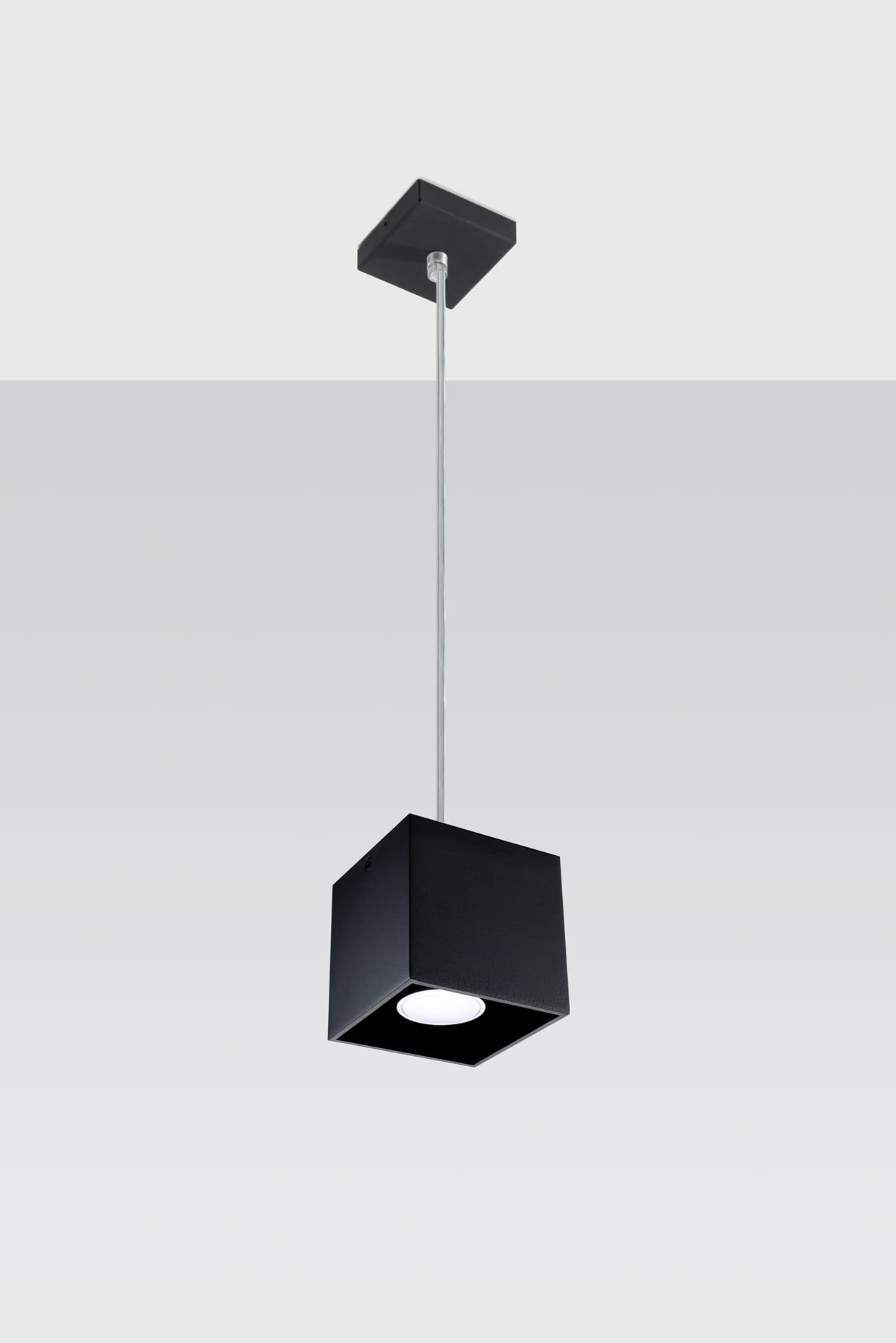 Czarna lampa wisząca 1-punktowa o kwadratowym kształcie, zawieszona na cienkim metalowym kablu. Ma matową powierzchnię i prosty design, idealna do nowoczesnych wnętrz. Widoczne źródło światła w dolnej części lampy.