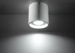 Biała lampa sufitowa 1-punktowa Orbis SL.0021, cylindryczny kształt, matowa powierzchnia. Widok z dołu, skierowana w dół, emitująca jasne światło. Proste tło podkreślające minimalistyczny design.