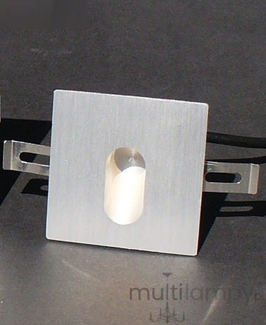 Oprawa schodowa Lesel LED 001 L w kolorze srebrnym, kwadratowa, z wycięciem na LED w centrum. Widać metalowe mocowania po bokach. Produkt leży na ciemnym tle, co podkreśla jego kształt i teksturę.